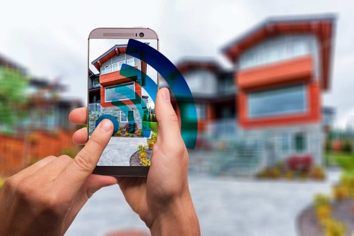 Mani muovono un'app sullo smartphone per gestire la casa che si vede sullo sfondo